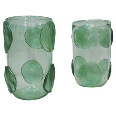 two green glass vases sitting side by side on a white background, each with different shapes and sizes