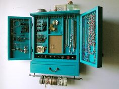 a blue cabinet with jewelry hanging from it's sides