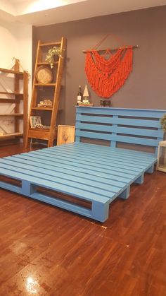 a bed frame made out of pallets in a room with hardwood floors and blue walls