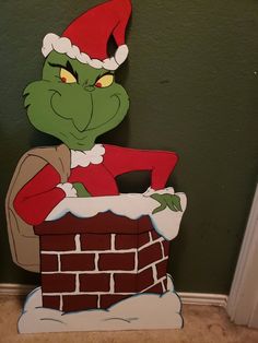 a cardboard cut out of the grin on top of a brick chimney with a santa hat