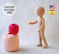 a crochet doll standing next to a ball of yarn