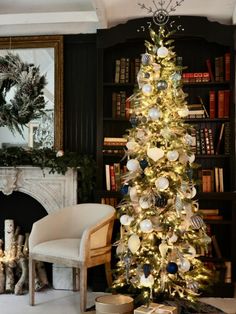 a decorated christmas tree in the corner of a room with bookshelves and fireplace