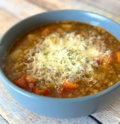 a blue bowl filled with soup on top of a wooden table