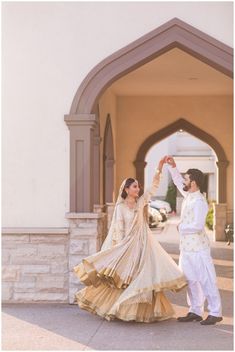 a bride and groom dancing in front of an archway