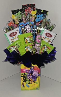 an assortment of candy and snacks in a gift box with ribbon tied around the bottom