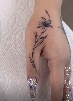 a woman's hand with a flower tattoo on it and a diamond in the middle