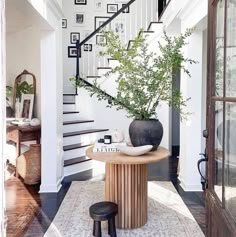 there is a potted plant on the table in front of the stair case that leads up to the second floor