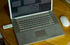 an open laptop computer sitting on top of a wooden table next to a white mouse