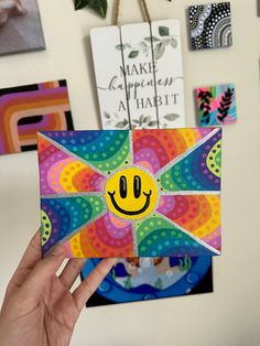 a person holding up a piece of paper with a smiley face on it in front of some pictures