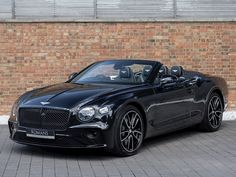 a black convertible car parked in front of a brick wall