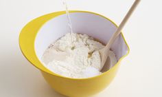 a yellow bowl filled with white powder and a wooden spoon