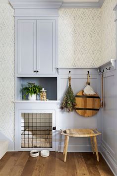 a dog crate in the corner of a room with white walls and wood flooring