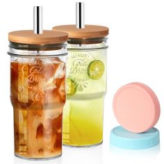 two mason jars filled with iced drinks next to a blue lid on a white background