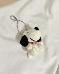 a crocheted dog keychain is laying on a white sheet with a red collar