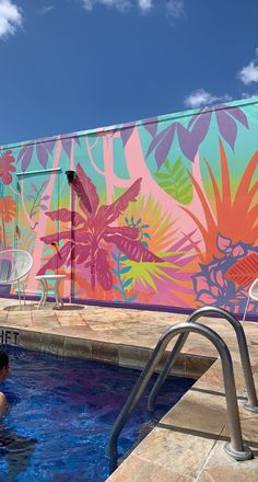 a man sitting in a pool next to a colorful wall