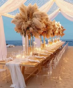 a long table set up on the beach with candles and pamolite centerpieces