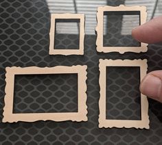 someone is holding three small square frames in their hand, and they are all made out of wood