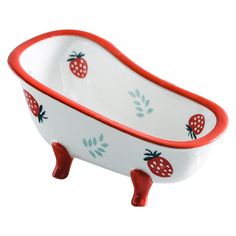 a red and white ceramic bathtub with strawberries on the rim, sitting in front of a white background