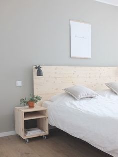 a bed with white sheets and pillows on top of it next to a wooden night stand