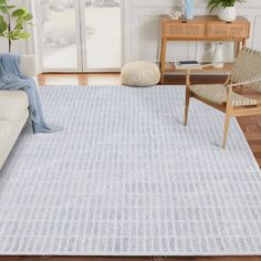 a living room with a white couch and blue rug