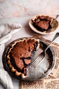 there is a pie on the table with a fork in it and an old newspaper next to it