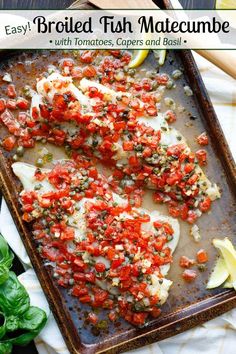 fish fillets with tomatoes, capers and basil on a baking sheet next to lemon wedges