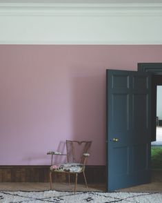 an empty chair sits in front of a pink wall and blue door that leads to a patio