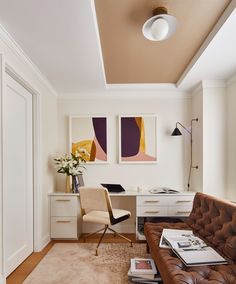 a living room filled with furniture and paintings on the wall above it's desk