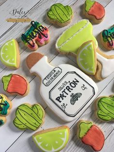 some decorated cookies are sitting on a white wooden table and there is a bottle of lemonade next to them