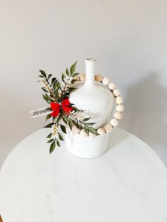 a white vase sitting on top of a table next to a wooden beaded bracelet