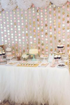 a table topped with cakes and desserts under paper stars hanging from the ceiling above it