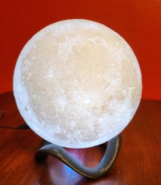 a large white ball sitting on top of a wooden table next to a lamp shade