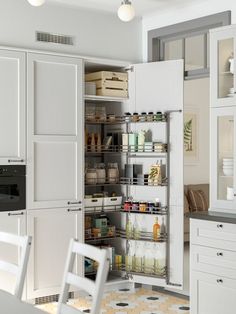 an open refrigerator in a kitchen with white cabinets