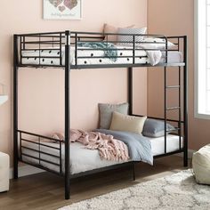 a black metal bunk bed sitting on top of a wooden floor next to a pink wall