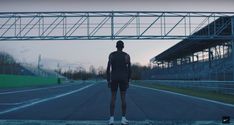 a man standing on the side of a road under an overpass that reads breaking the two hour marathon barrier