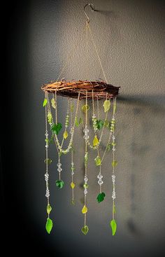 a piece of wood hanging from the side of a wall with green and white beads attached to it