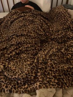 a woman laying in bed with a leopard print comforter