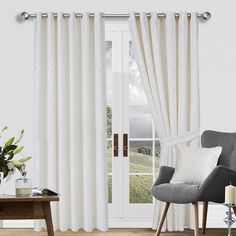 a living room with white curtains and a gray chair