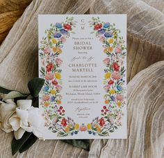 the wedding stationery is laid out on top of a bed with flowers and greenery