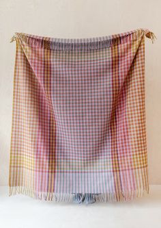 a plaid blanket with tassels hanging from it's end on a white surface