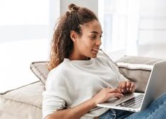 a woman sitting on a couch using a laptop computer