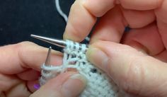 someone crocheting the end of a piece of white yarn with two hands holding it