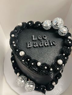 a black heart shaped cake with the words le badne written on it, surrounded by crystal balls