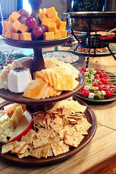 three tiered platters filled with cheese, crackers and fruit on top of a wooden table