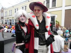 two people dressed up in costumes standing next to each other on a city street with lots of people behind them