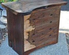 a wooden dresser sitting on top of a cement floor next to a flower potted plant