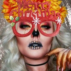 a woman with bright makeup and flowers on her head wearing a red mask that says merry christmas