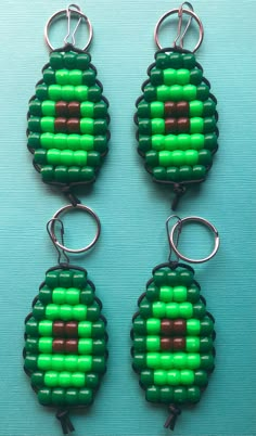 three pieces of green and brown bead with metal hooks on a blue table top