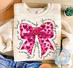 a t - shirt with a pink bow and hearts on it, sitting next to some shoes