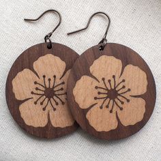 two wooden earrings with flower designs on them